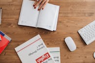 Open planner and English workbooks on a wooden desk, ideal for study-themed visuals.